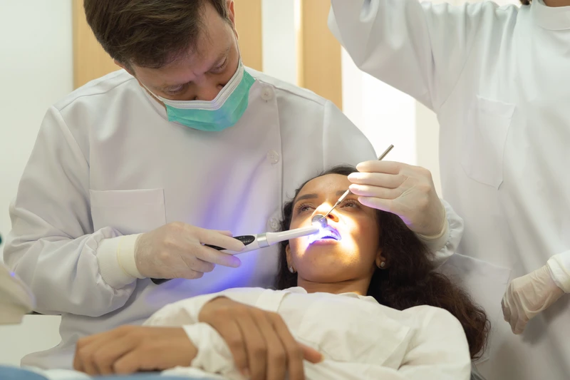 A dentist checking up a woman patient's teeth by using dental mouth mirror at hospital clinic. Teeth check up with dental tools. Doctor. Dentistry, medical and health. People.